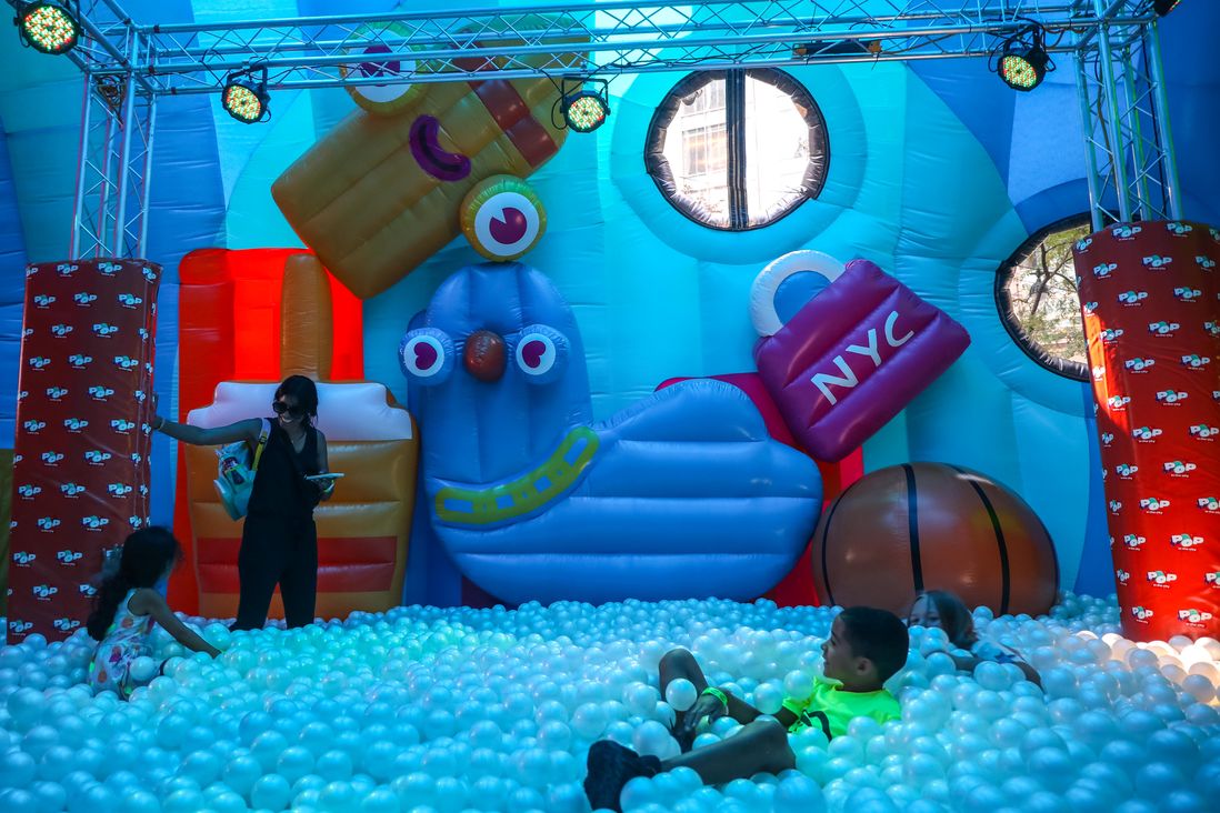 A recreational installation filled with balls, inflated figures and people.